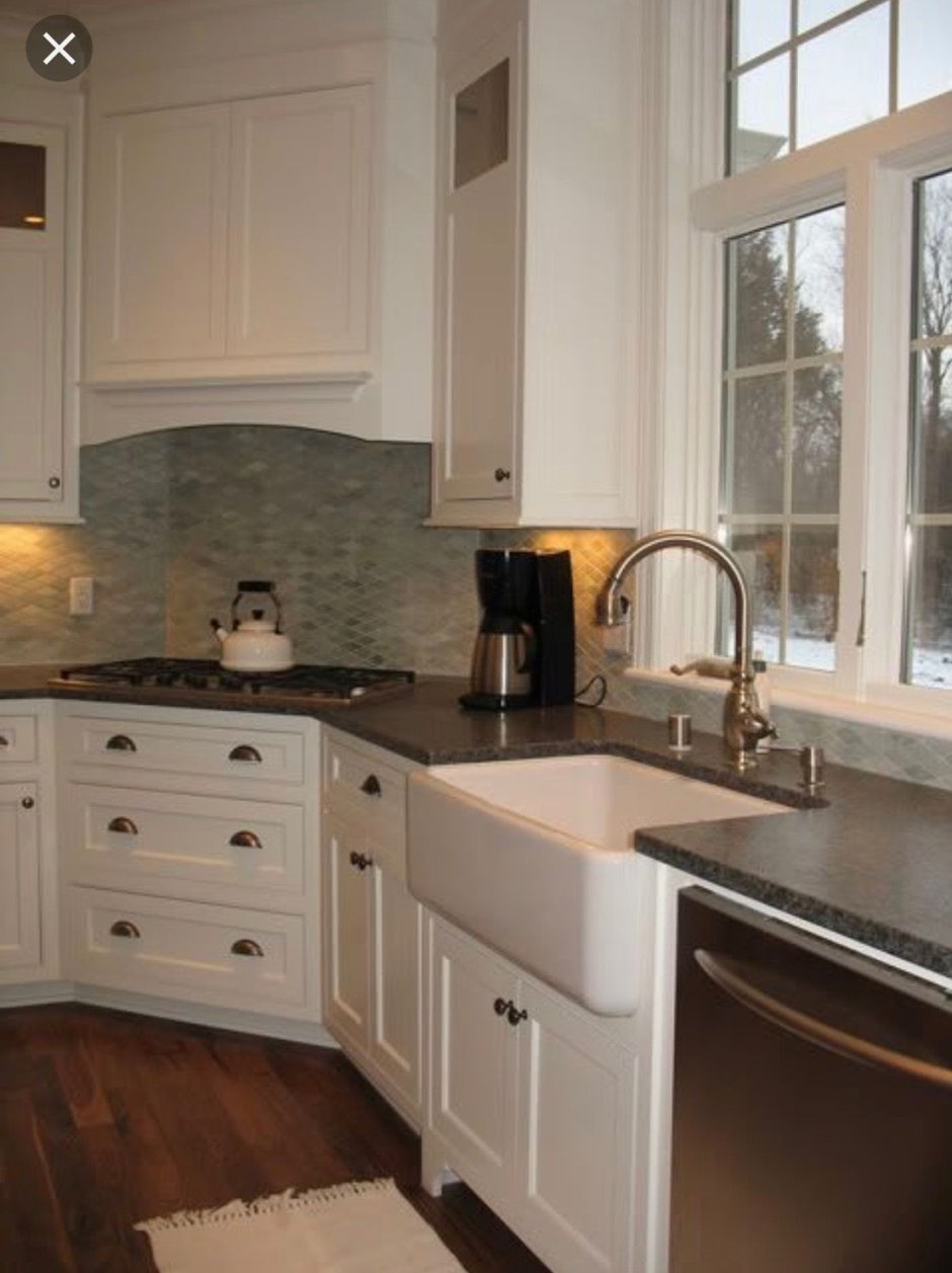 Кухня с плитой в углу и раковиной у окна