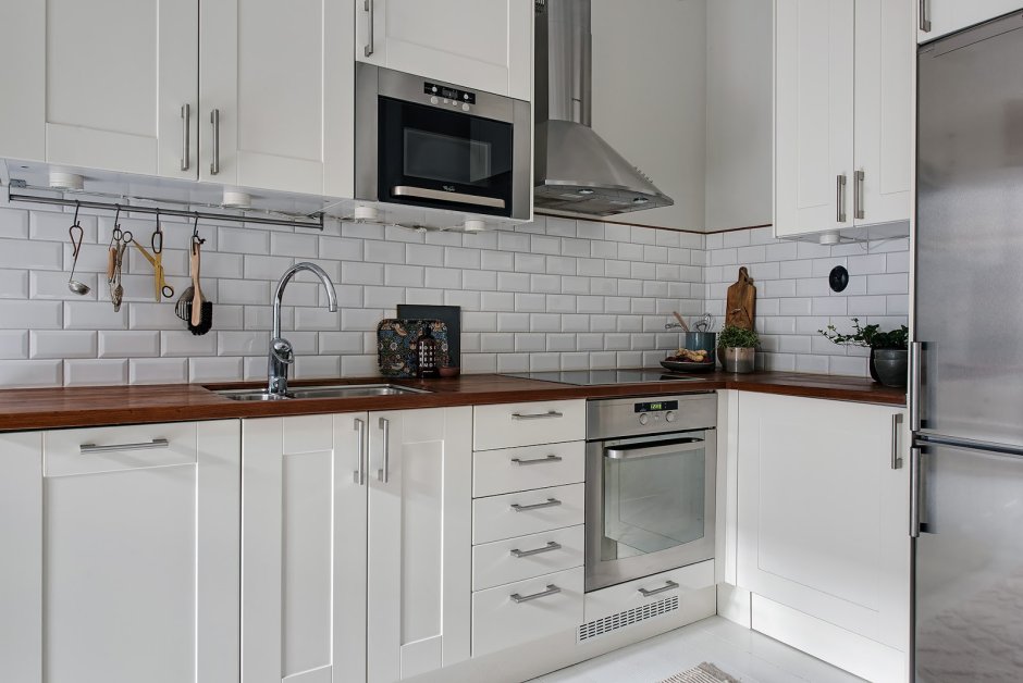 Белая кухня с деревянной столешницей и белым фартуком