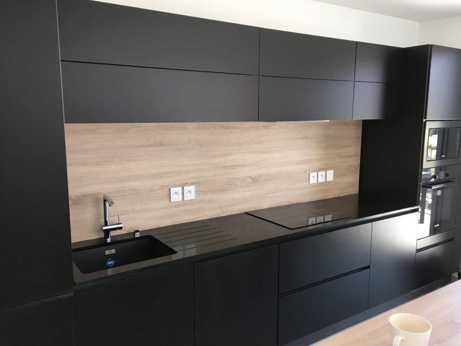 Кухня с черным фартуком и столешницей и дерево