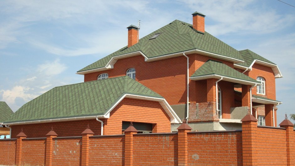 Красный кирпичный дом с зеленой крышей