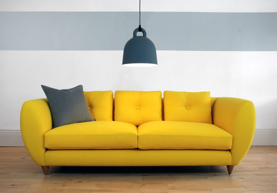 Белый диван на фоне желтой стены
