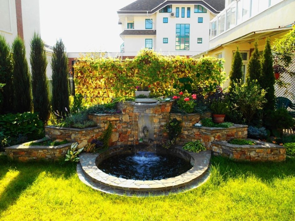 Фонтан во дворе с клумбой